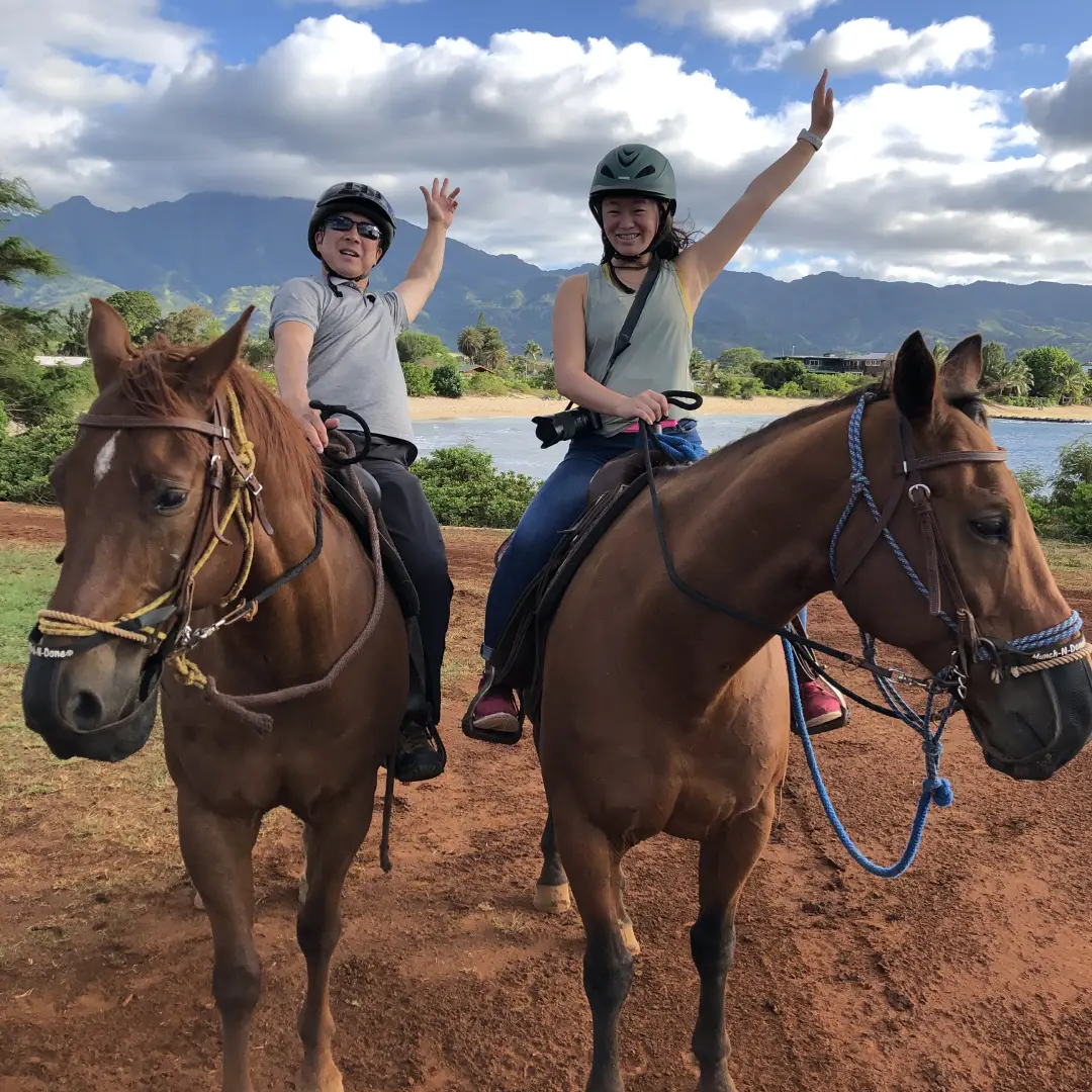 People horseback riding and waving to the camera happily